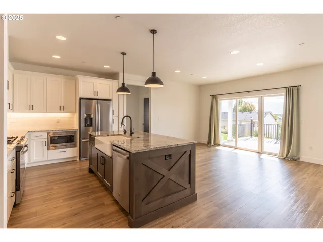 a open kitchen with kitchen island a sink dishwasher a stove and a refrigerator with wooden floor