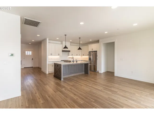 a view of an empty room with wooden floor and fireplace