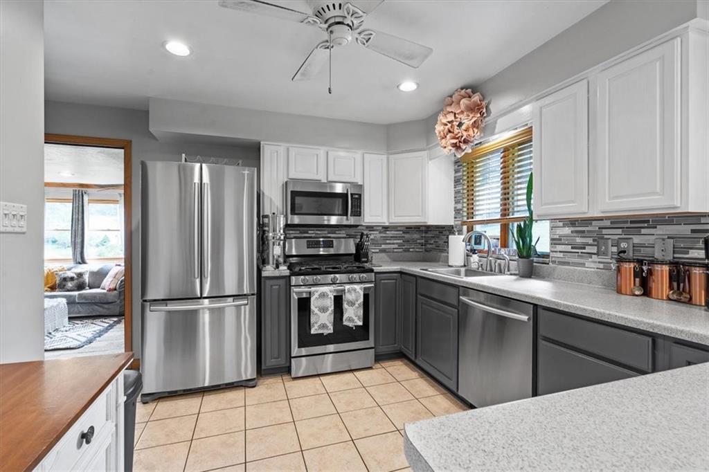 21 Ellen Drive McKees Rocks, PA 15136 - Photo 10 of 24 a kitchen with stainless steel appliances granite countertop a refrigerator a sink dishwasher a stove and white cabinets with wooden floor
