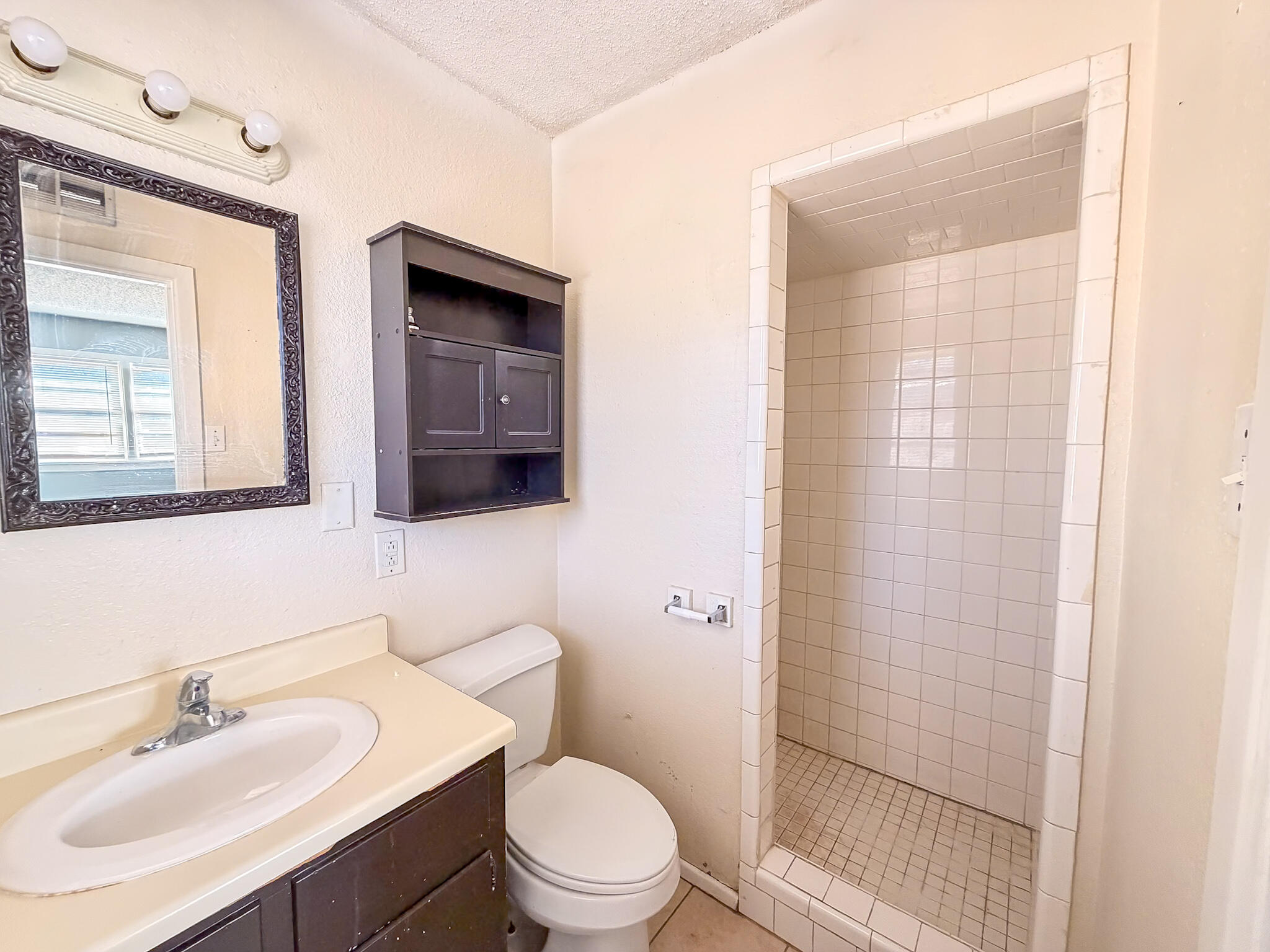 2805 53rd Street Lubbock, TX 79413 - Photo 3 of 13 a bathroom with a toilet a sink a mirror and shower