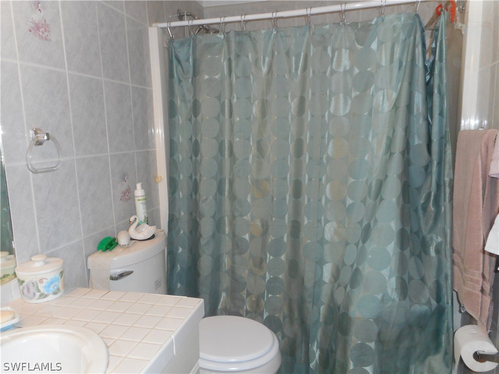 8470 Robin Road Fort Myers, FL 33967 - Photo 19 of 24 a bathroom with a sink a toilet and shower curtain