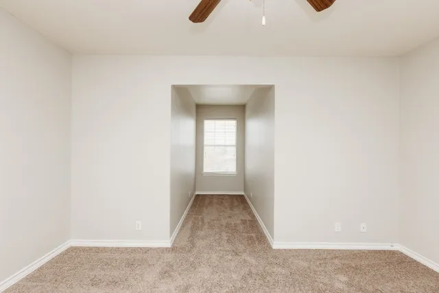 a view of an empty room with closet and a window