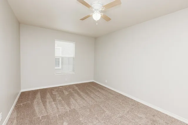 an empty room with a window and a ceiling fan