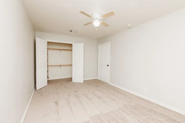 an empty room with closet and a ceiling fan