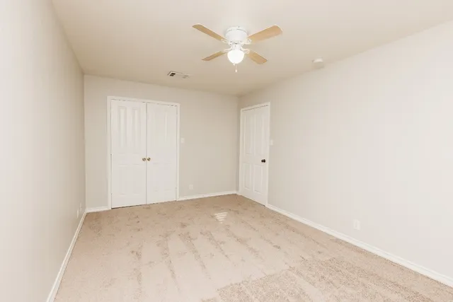 an empty room with closet and a ceiling fan