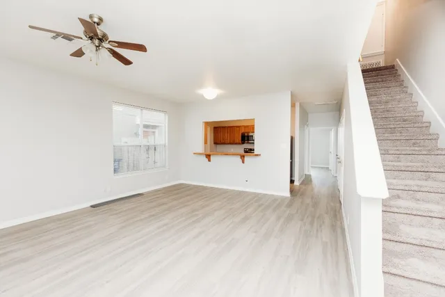 an empty room with wooden floor fan and windows