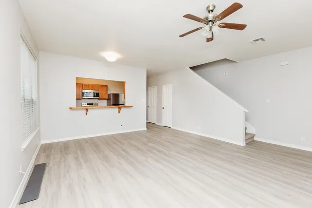 a view of a big room with wooden floor and a ceiling fan