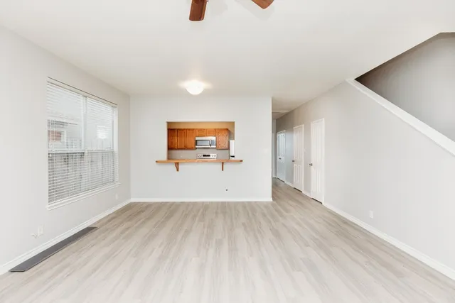 a view of empty room with wooden floor and fan