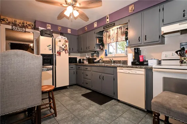 a kitchen with a refrigerator a sink dishwasher a stove and white cabinets with wooden floor