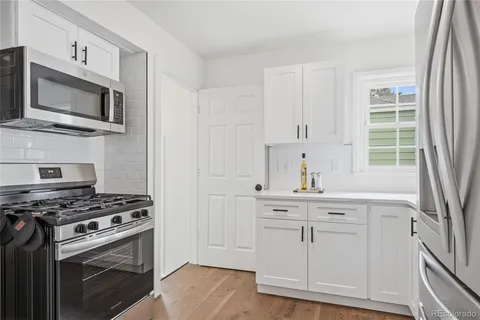 a kitchen with white cabinets and a window
