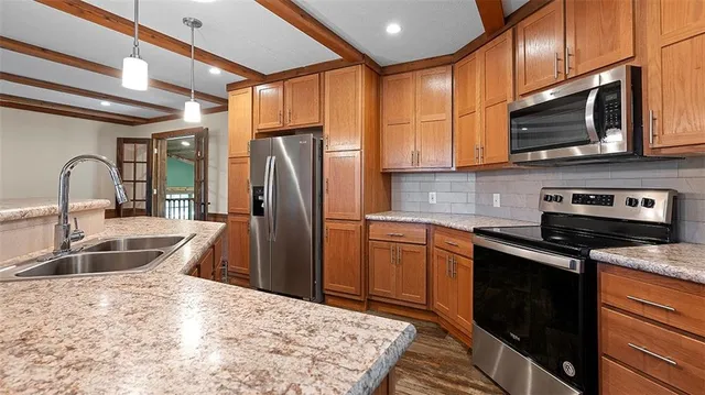 a kitchen with stainless steel appliances granite countertop a sink a refrigerator and a stove