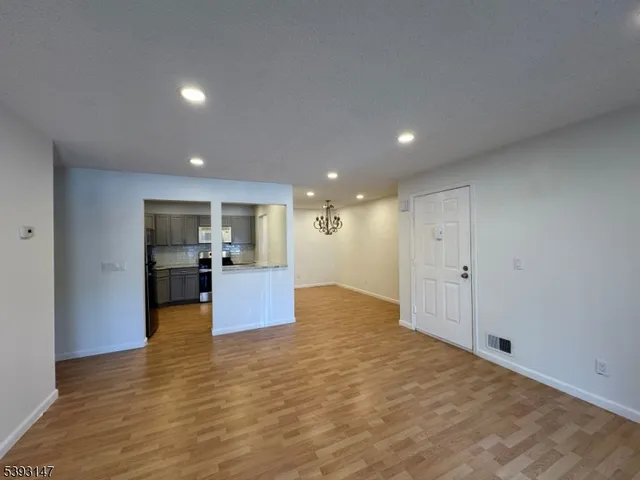 a view of a kitchen with kitchen island stainless steel appliances counter space and wooden floor