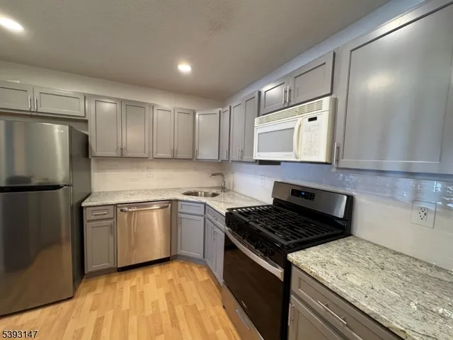 a kitchen with stainless steel appliances granite countertop a stove a sink and a refrigerator