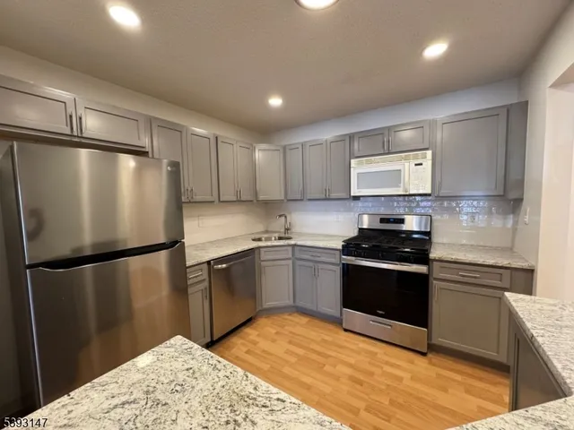 a kitchen with stainless steel appliances granite countertop a refrigerator a stove and a sink