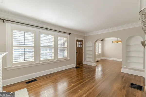 a view of an empty room with wooden floor fireplace and a window