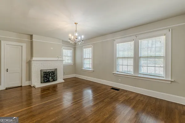 an empty room with wooden floor fireplace and windows