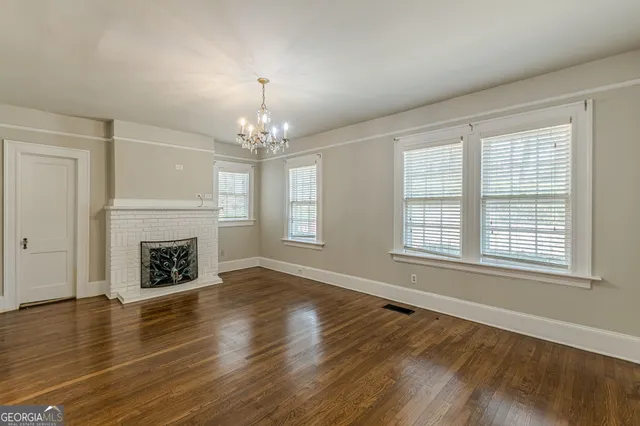 an empty room with wooden floor fireplace and windows