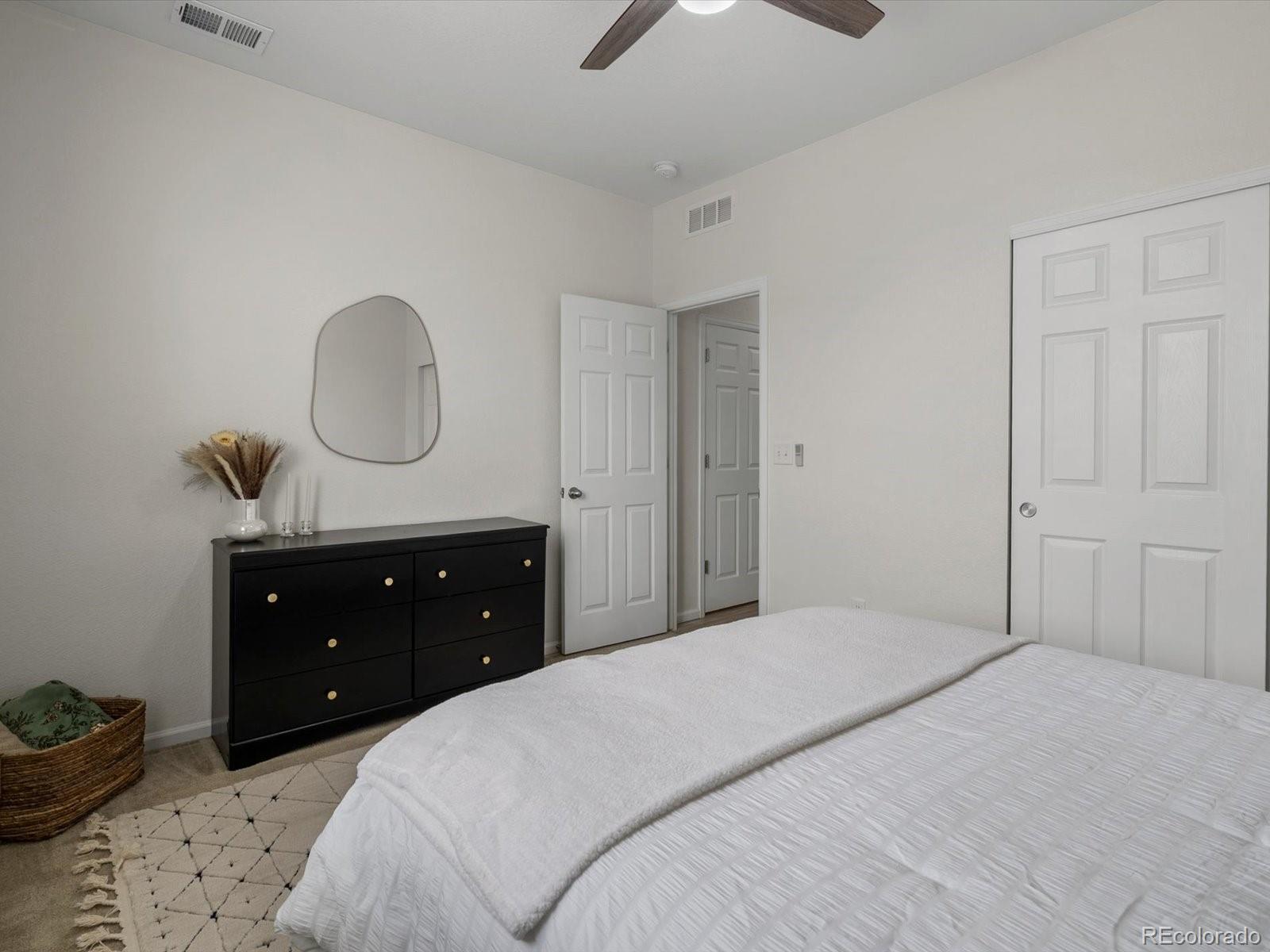 5347 Warrior Street Frederick, CO 80504 - Photo 32 of 48 a bedroom with a bed a lamp and a dresser