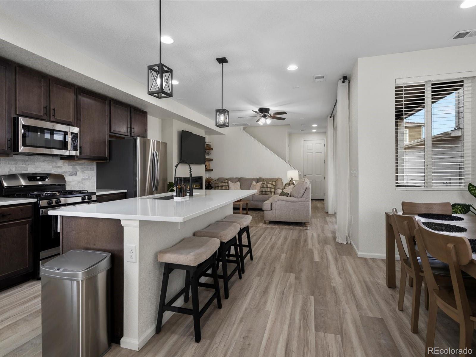 5347 Warrior Street Frederick, CO 80504 - Photo 6 of 48 a kitchen with stainless steel appliances granite countertop a stove refrigerator a oven a dining table and chairs with wooden floor