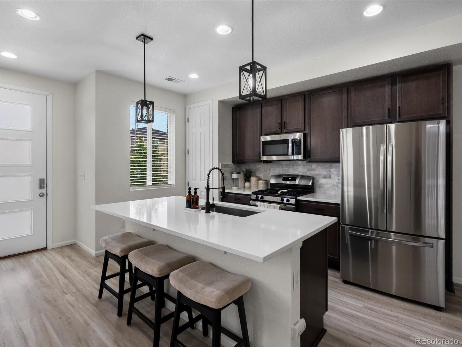 5347 Warrior Street Frederick, CO 80504 - Photo 8 of 48 a kitchen with kitchen island a wooden floor and refrigerator