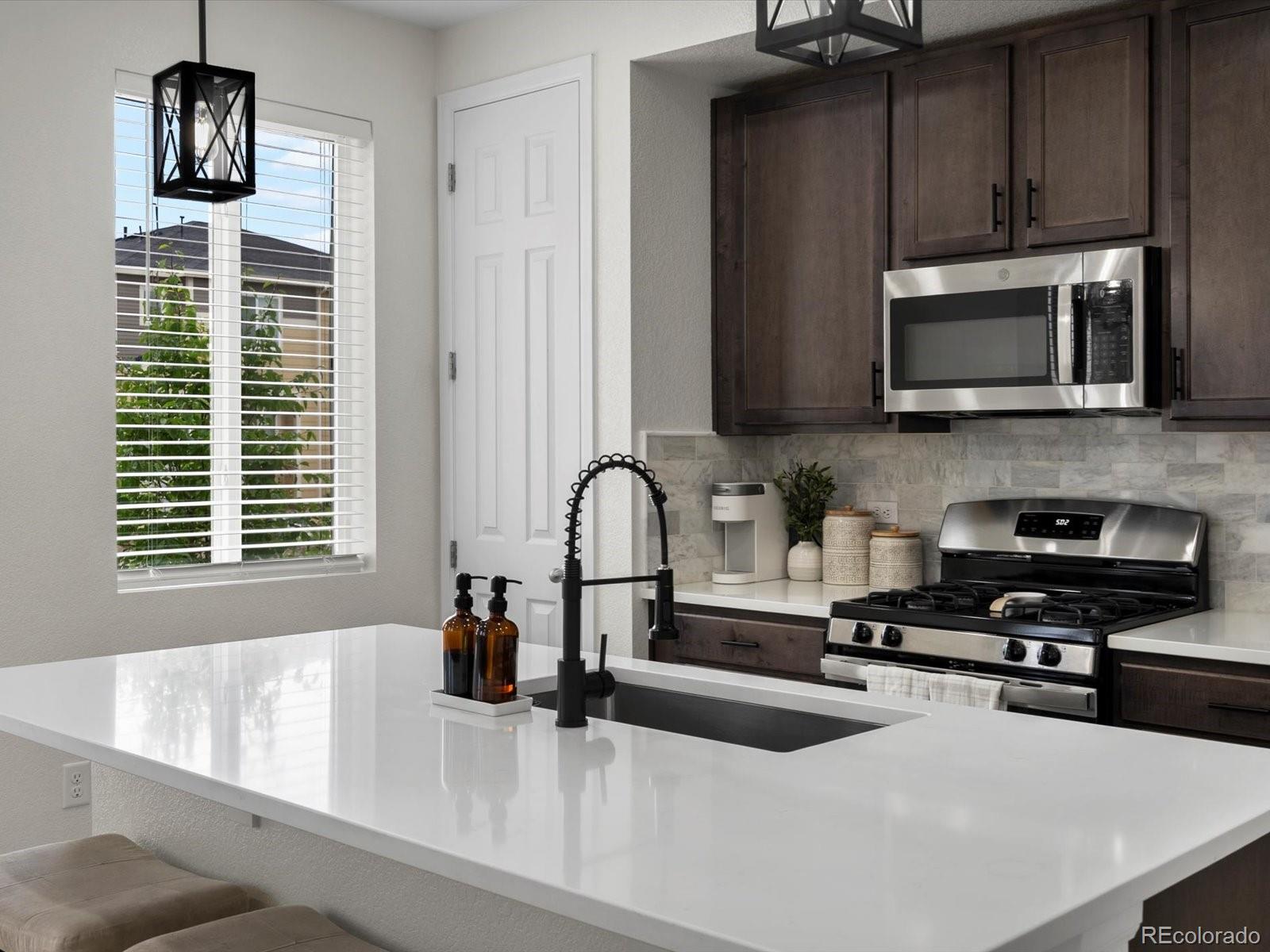 5347 Warrior Street Frederick, CO 80504 - Photo 9 of 48 a kitchen with stainless steel appliances a sink a stove a microwave and cabinets
