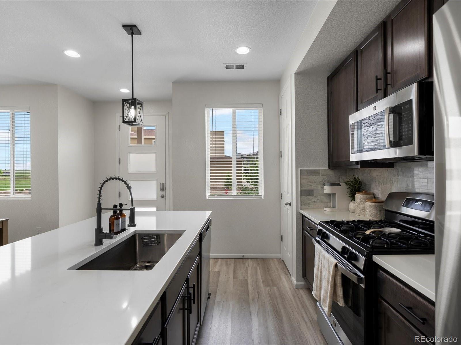 5347 Warrior Street Frederick, CO 80504 - Photo 10 of 48 a kitchen with stainless steel appliances granite countertop a sink stove a refrigerator and cabinets with wooden floor