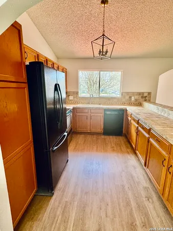 a kitchen with stainless steel appliances granite countertop a refrigerator a sink dishwasher a stove and white countertops with wooden floor