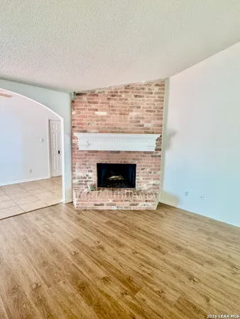 a view of empty room with wooden floor and fireplace