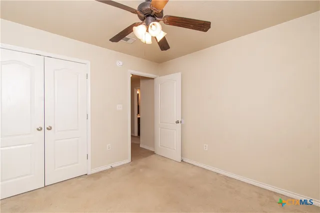 an empty room with closet and a chandelier fan