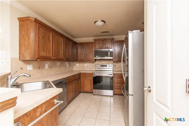 a kitchen with stainless steel appliances granite countertop a refrigerator sink and stove