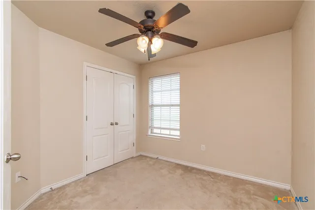 an empty room with windows and fan