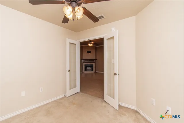 an empty room with an entryway and kitchen view