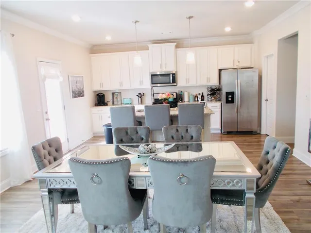 a dining room with stainless steel appliances kitchen island granite countertop a table chairs and a refrigerator