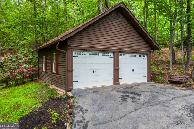 a view of a house with a yard plants and large tree