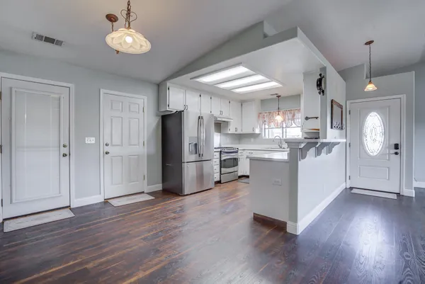 an empty room with wooden floor cabinet and windows