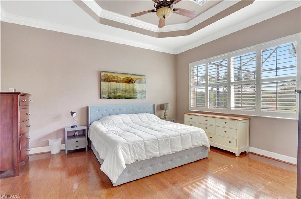 7903 Founders Circle Naples, FL 34104 - Photo 21 of 32 a bedroom with a large bed and a chandelier fan