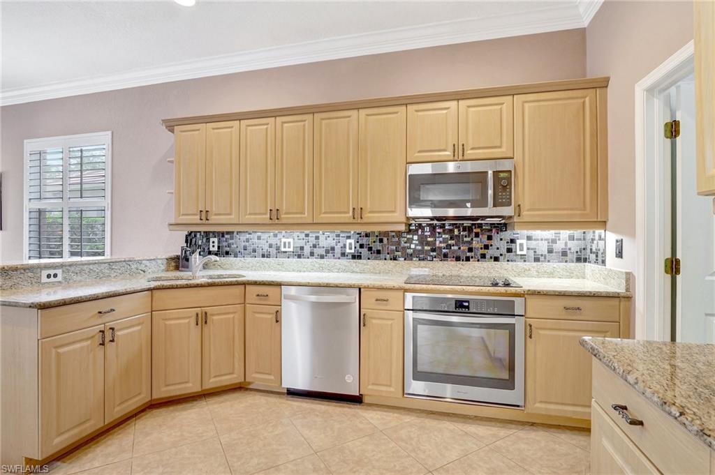 7903 Founders Circle Naples, FL 34104 - Photo 9 of 32 a kitchen with granite countertop white cabinets sink and stainless steel appliances