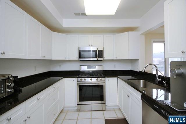 307 Jefferson Court Edgewater, NJ 07020 - Photo 12 of 36 a kitchen with granite countertop white cabinets and black appliances