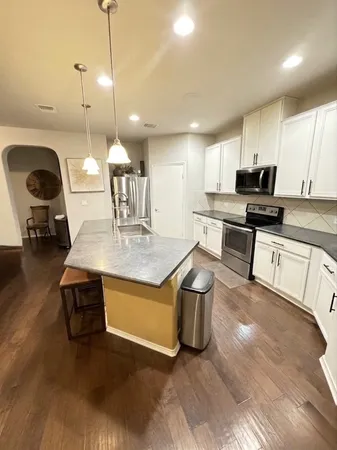 a kitchen with stainless steel appliances granite countertop a sink a stove and a wooden floors