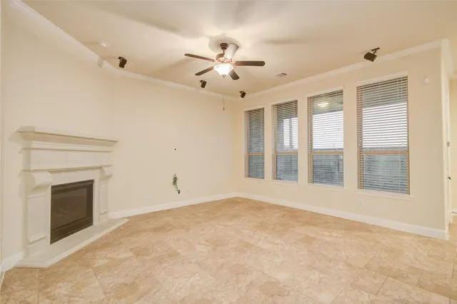 a view of an empty room with chandelier fan and fire place