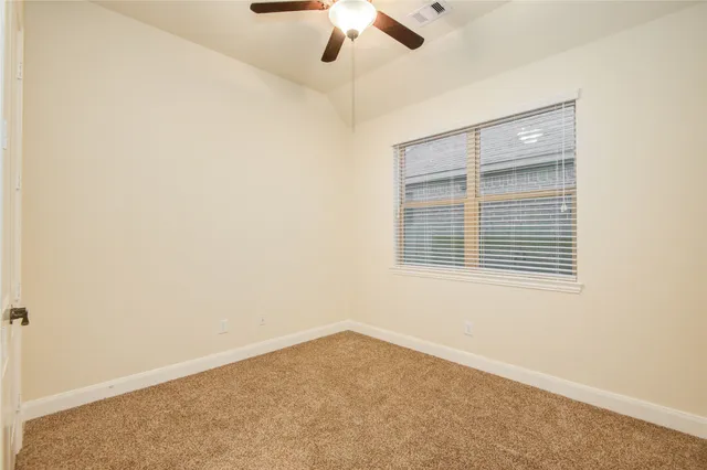 an empty room with a window and a fan