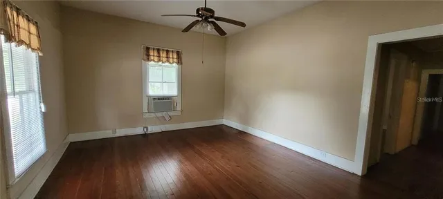 an empty room with wooden floor windows and entrance