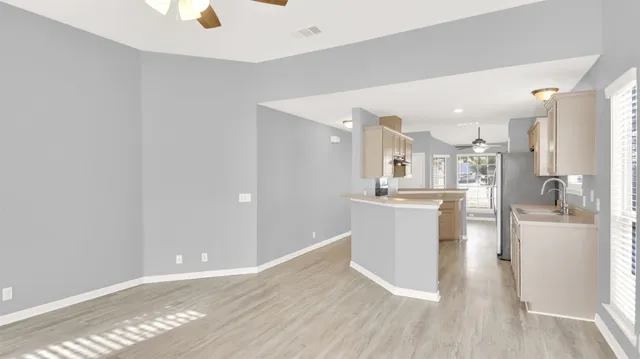 a view of a kitchen with kitchen island a sink wooden floor and stainless steel appliances