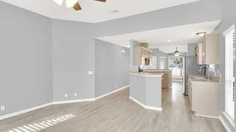 a view of a kitchen with kitchen island a sink wooden floor and stainless steel appliances
