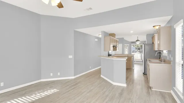 a view of a kitchen with kitchen island a sink wooden floor and stainless steel appliances