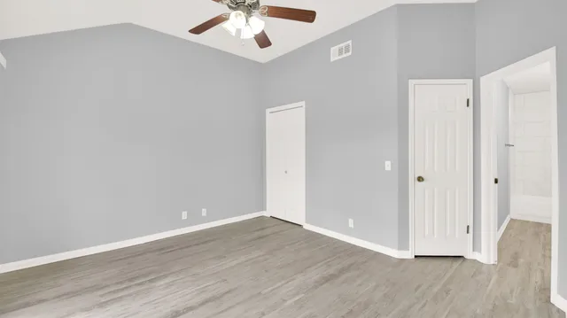 an empty room with wooden floor chandelier fan and entryway