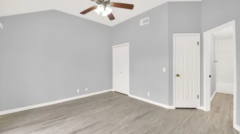 an empty room with wooden floor chandelier fan and entryway