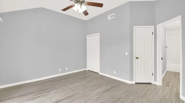 an empty room with wooden floor chandelier fan and entryway