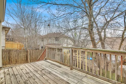 a view of a white house with a large tree and wooden fence