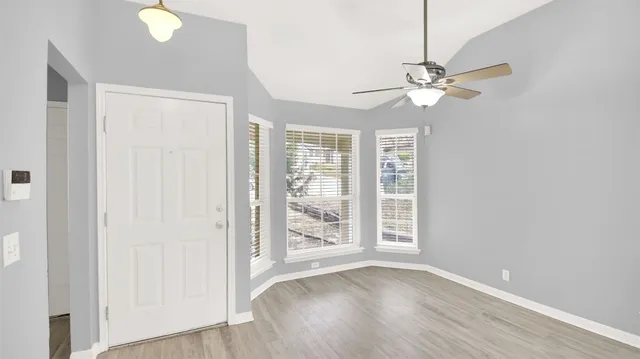a view of an empty room with a window and wooden floor